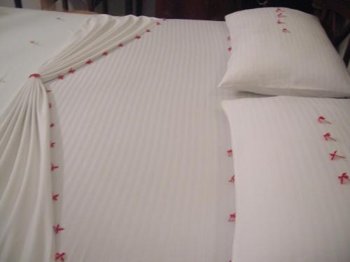 a bed with white sheets and pillows on it at Sagarika Beach Hotel in Moragalla