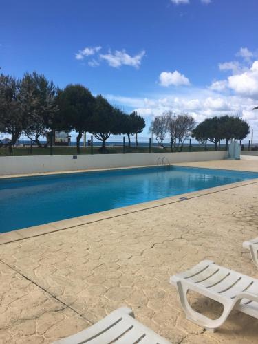 a swimming pool with two white lounge chairs next to it at Apartamento Praia Da Gaivota in Quarteira