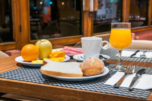 a table with a plate of food and a glass of orange juice at Hotel Los Olivos in Getafe