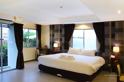 a bedroom with a large white bed with large windows at Suvarnabhumi Ville Airport Hotel in Lat Krabang