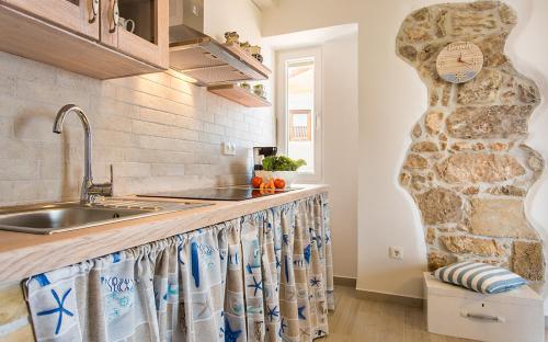 a kitchen with a sink and a stone wall at Apartman Bonaca in Vrbnik