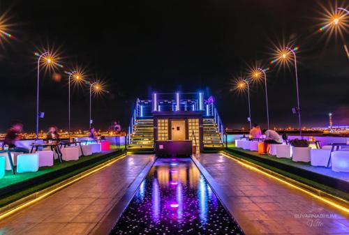a rooftop bar with tables and lights at night at Suvarnabhumi Ville Airport Hotel in Lat Krabang