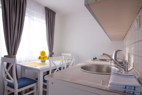 a kitchen with a sink and a table with chairs at Apartments Grand in Sveti Stefan