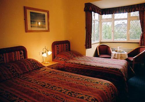 a hotel room with two beds and a window at Nonsuch Park Hotel in Epsom