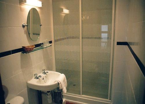 ein Bad mit einem Waschbecken und einer Glasdusche in der Unterkunft Nonsuch Park Hotel in Epsom