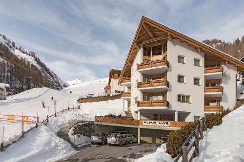a hotel with two cars parked in the snow at Appartements Garni Alpin Live in Samnaun