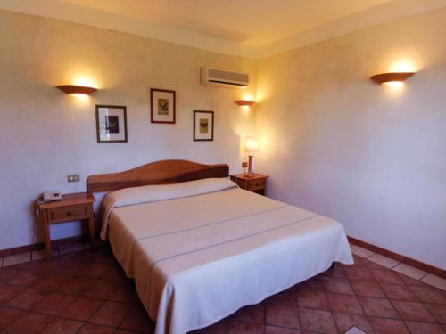 プーラにあるSpacious Holiday Home in Sardinia with Swimming Poolのベッド1台、壁にランプ2つが備わるホテルルームです。