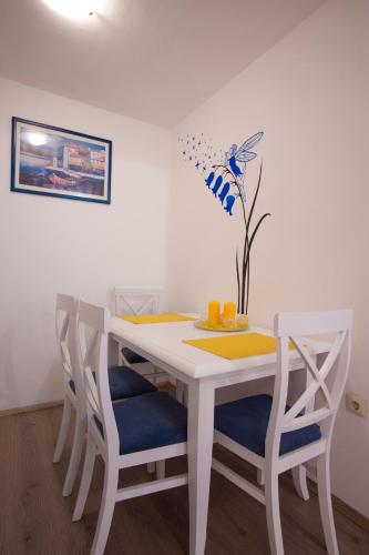 a white dining room table with four chairs and a vase at Apartments Grand in Sveti Stefan