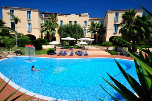 a person in a swimming pool in a hotel at Hotel Arbatasar in Àrbatax