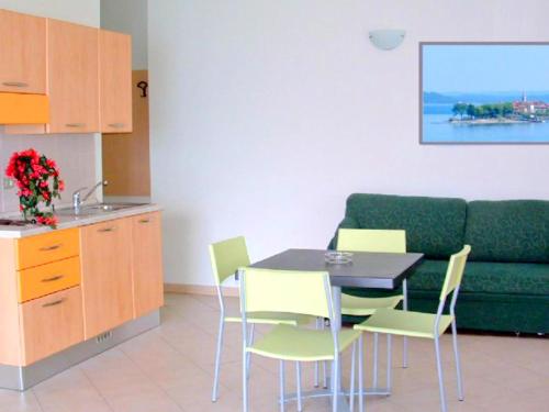 ヴェルバーニアにあるApartment in a residence on Lake Maggiore near the beachのリビングルーム(緑のソファ、テーブル、椅子付)