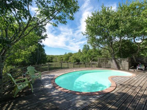 a swimming pool on a wooden deck with chairs and trees at Nice holiday home with pool in Ard che in Saint Alban Auriolles