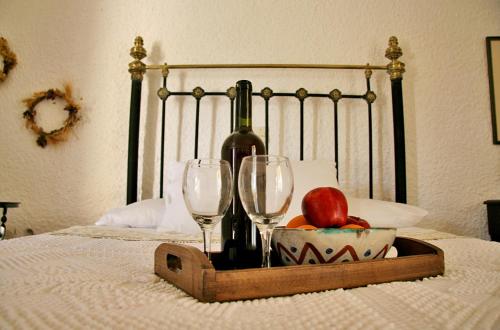 a tray of wine glasses and an apple on a bed at Vagia Traditional, Aegina Island in Vaia