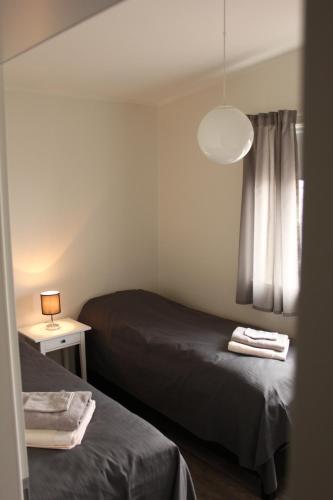 a bedroom with two beds and a lamp and a window at Grýtubakki I in Grenivík