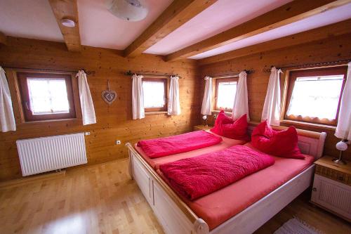 Cama en habitación de madera con almohadas rojas en Reitstall Henntalhof, en Kitzbühel