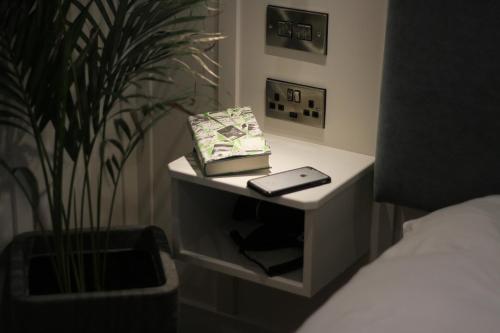 a table with a book and a phone on it next to a plant at Quinlan & Cooke Boutique Townhouse and QCs Seafood Restaurant in Cahersiveen