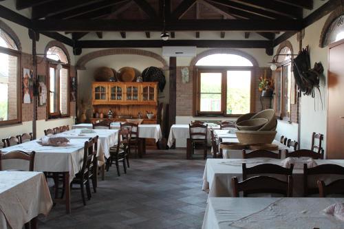 a restaurant with white tables and chairs and windows at Agriturismo Su Recreu in Ittiri