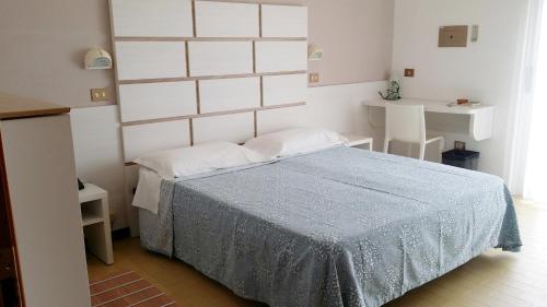 ein Schlafzimmer mit einem Bett mit einer blauen Decke in der Unterkunft Hotel La Falena in Cervia