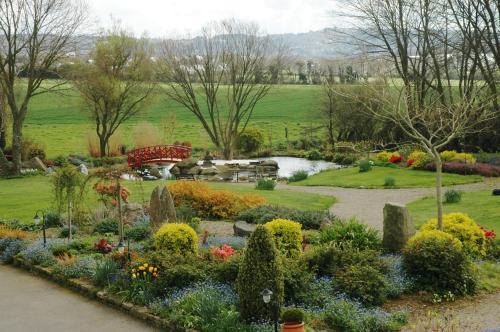 a garden with flowers and a pond in a park at Chambres d'Hotes Belard in Plonévez-Porzay