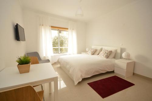 a white bedroom with a bed and a window at Parque dos Pastores in Fátima