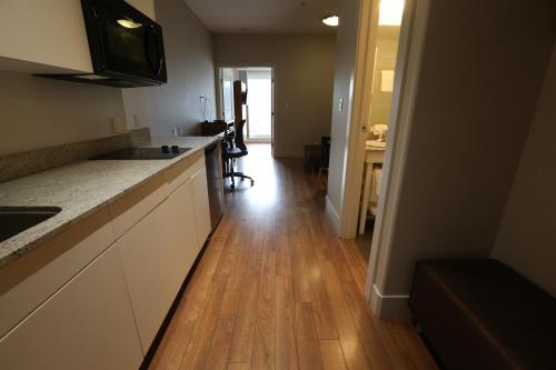 a kitchen with white cabinets and a wooden floor at Baymont by Wyndham Fort McMurray in Fort McMurray