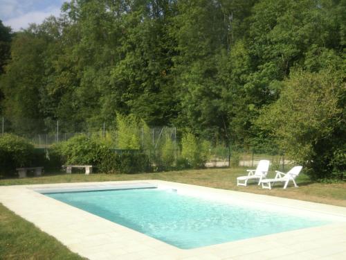 een zwembad in een tuin met twee stoelen bij Superb villa with private heated pool in Revigny-sur-Ornain
