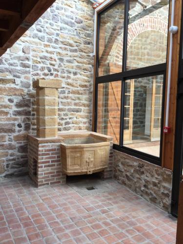 a stone building with a tub in front of a window at Contact Hôtels Le Savigny & Spa in Blacé