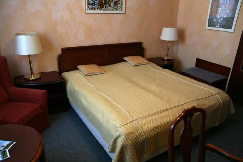 a bedroom with a bed with two lamps and a chair at Hotel Alfacentrum in Valašské Klobouky