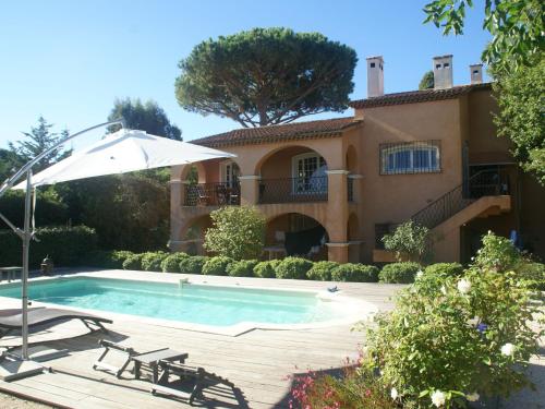 サントロペにあるModern holiday home with private gardenのスイミングプールと傘付きの家