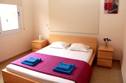 Un dormitorio con una cama con dos almohadas azules encima. en Photothea Apartments, en Protaras