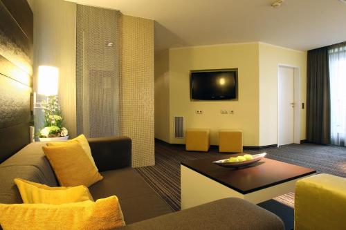 a living room filled with furniture and a tv at Congress Hotel am Stadtpark in Hannover