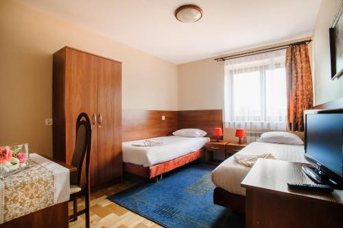 a hotel room with two beds and a desk at Hotel Galicja in Ulanów