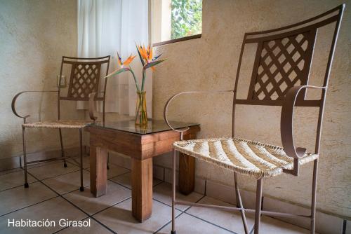 two chairs and a table and a vase with flowers on it at Flor de Cera in Tepoztlán
