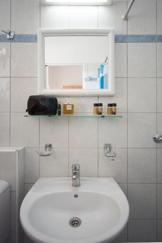 a white bathroom with a sink and a mirror at Metaxa Apartments in Kavos