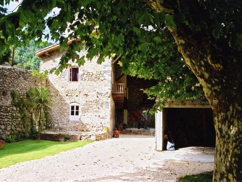 un grand bâtiment en pierre avec un arbre devant dans l'établissement Holiday Home in Ardèche near Château Ventadour, à Lalevade-dʼArdèche