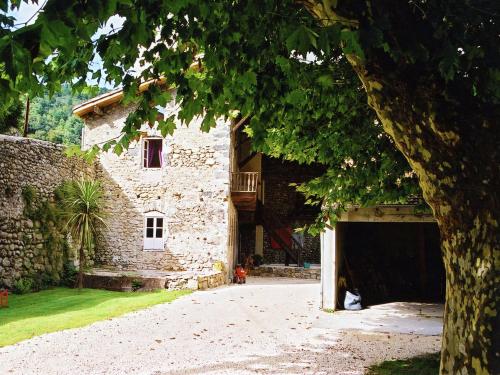a large stone building with a tree in front of it at Pretty Holiday Home in Ard che with Swimming Pool in Lalevade-dʼArdèche