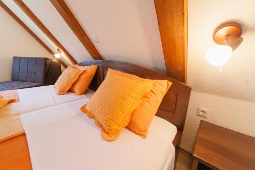 a small room with two beds with orange pillows at Guest House Rustico in Korenica