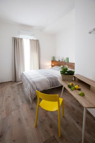a bedroom with a bed and a yellow chair at Porta degli Antichi Casali in Conversano
