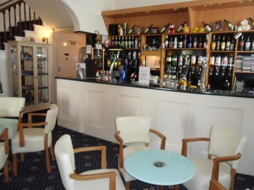 a bar with white chairs and a blue table at Nethway Hotel in Torquay