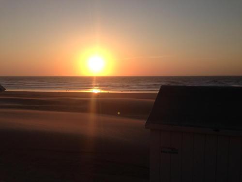 a sunset on the beach with the ocean at Comfort Aan Zee Guestrooms in Ostend