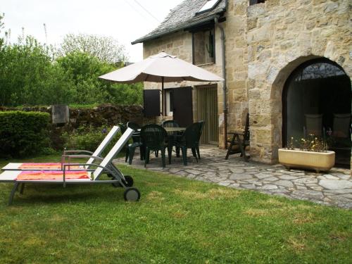姆勒莎圖的住宿－Vintage holiday home near Rodez in Aveyron，庭院配有遮阳伞和桌椅。