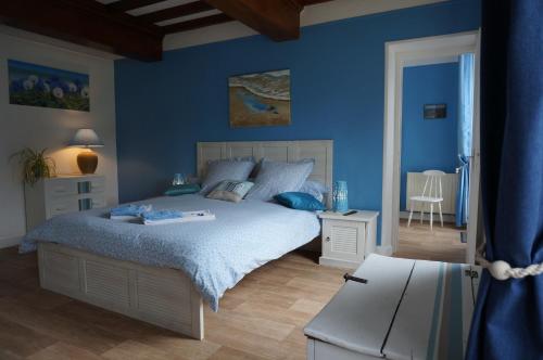Sainte-Honorine-des-PertesにあるLe Clos Saint Jeanの青い壁のベッドルーム1室、ベッド1台、テーブルが備わります。