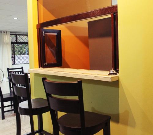 a bar with four chairs and a mirror at Hostal de Asturias in San Salvador