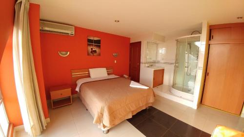 een slaapkamer met oranje muren en een bed en een raam bij Libertad Hotel in Trujillo
