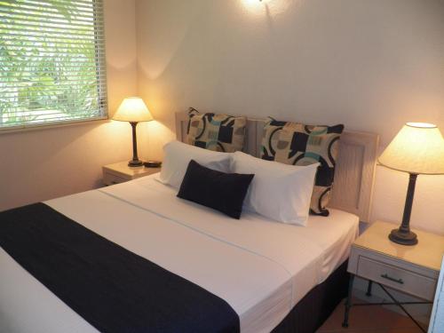 Un dormitorio con una gran cama blanca con dos lámparas. en Palm Cove Tropic Apartments, en Palm Cove