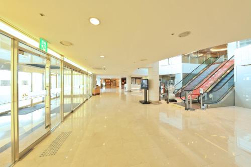 an empty lobby with an escalator in a building at Ocean Suites Jeju Hotel in Jeju