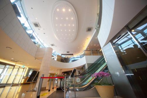 an escalator in a shopping mall with a large ceiling at Ocean Suites Jeju Hotel in Jeju