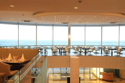 a restaurant with tables and chairs and large windows at Ocean Suites Jeju Hotel in Jeju
