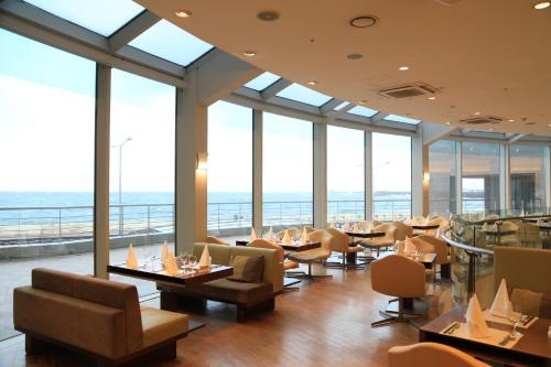 a restaurant with tables and chairs and windows at Ocean Suites Jeju Hotel in Jeju