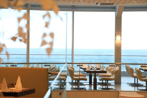 a restaurant with tables and chairs and windows at Ocean Suites Jeju Hotel in Jeju