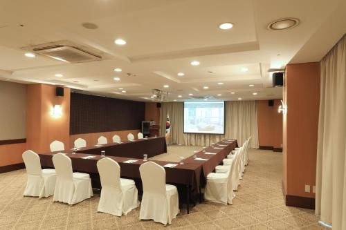 a conference room with a long table and white chairs at Ocean Suites Jeju Hotel in Jeju